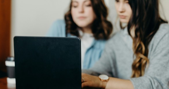 Two young women focused on working together on a laptop, representing collaboration and productivity in a modern digital environment.