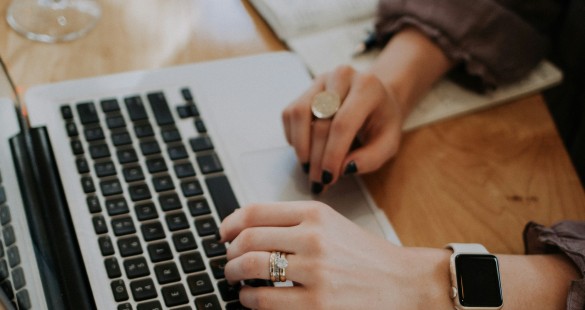 Close-up of a person's hands typing on a laptop, with a notebook in the background, representing productivity and digital work.