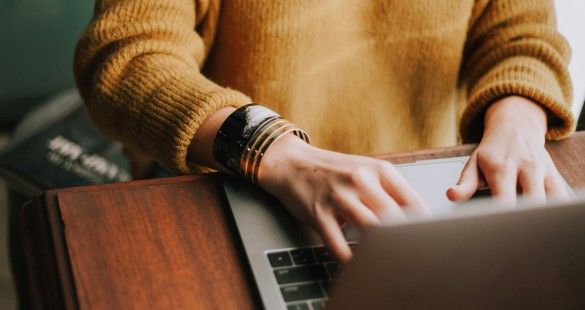 Person in a yellow sweater typing on a laptop, representing casual and productive work environment to Enhance Workflow with AI Chat.