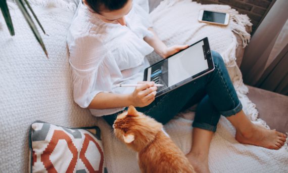 A girl chilling on the couch doing graphic designs.